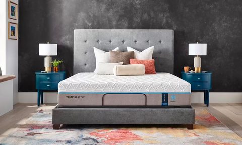 Tempur-Pedic’s Breeze 2.0 mattress is place on a bed frame and covered with pillows in a bedroom.