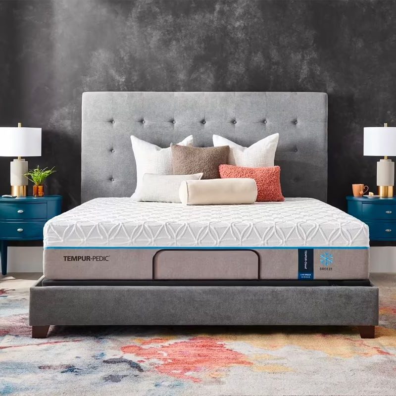 Tempur-Pedic’s Breeze 2.0 mattress is place on a bed frame and covered with pillows in a bedroom.