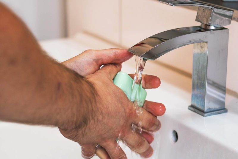 A man washes his hands with soap and water in a sink.