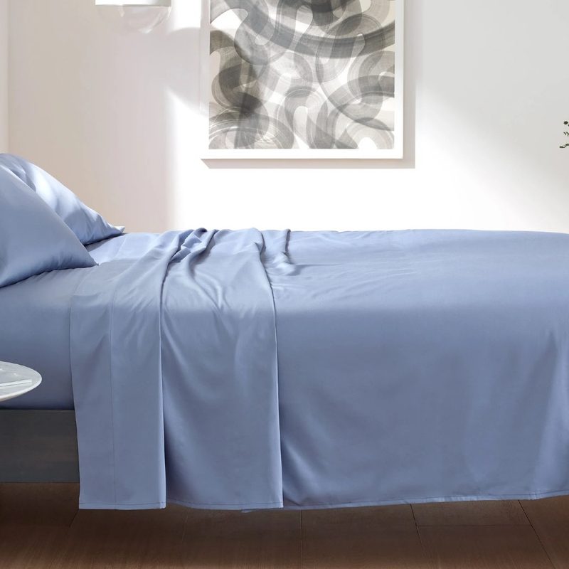 A set of slate blue Clean Design Home x Martex bed sheets on a bed.