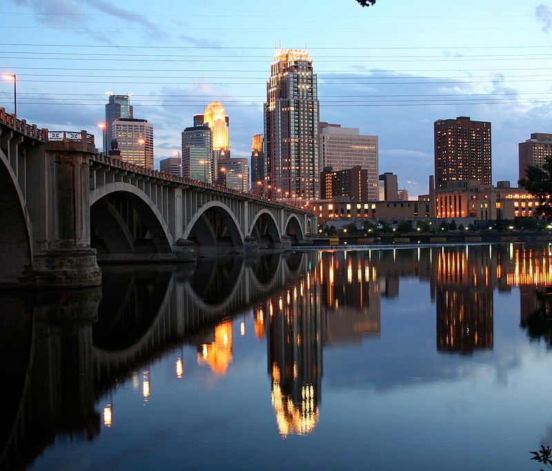 A view of the Minneapolis, Minnesota skyline with the Mississippi River and a bridge in the foreground
