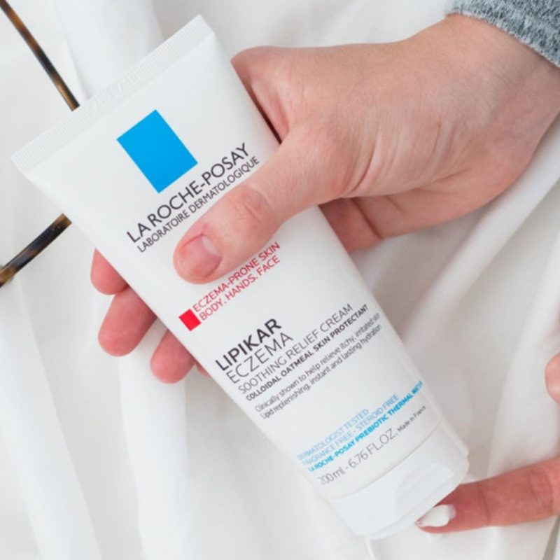 Someone holds a bottle of La Roche-Posay Lipikar Eczema Soothing Relief Cream.
