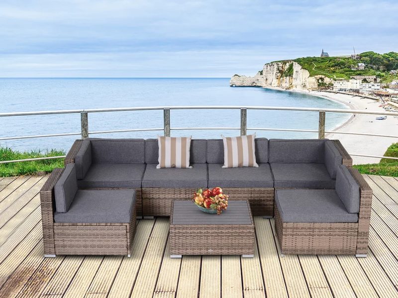 Merton sectional seating group with cushions on a wooden deck overlooking water.
