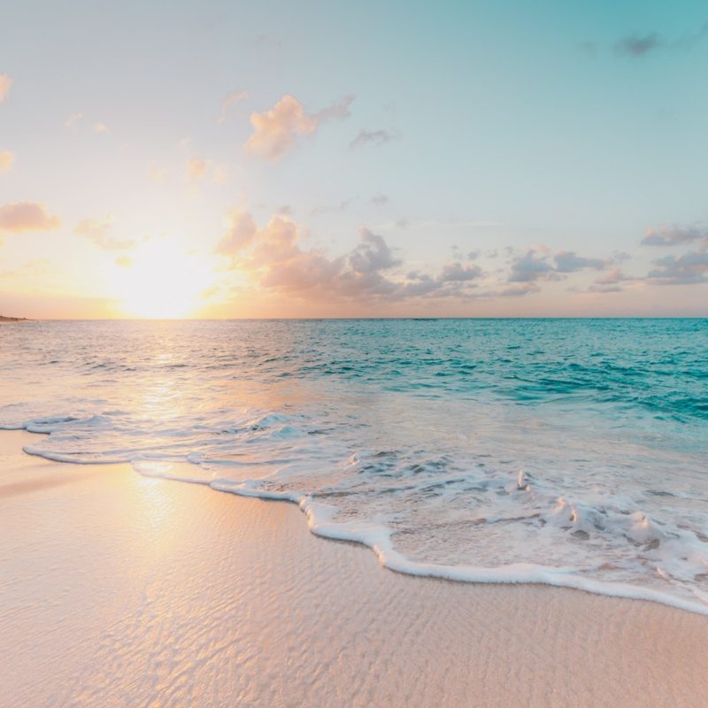 sunset on the beach with waves crashing.