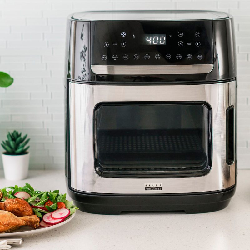 Bella Pro 12.6-quart Pro digital air fryer oven with a prepared meal of chicken drumsticks and salad.