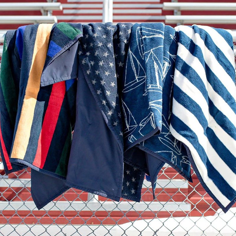 The entire collection of ChappyWrap Fair Winds Navy Water Resistant Outdoor Blankets hang out at the stadium