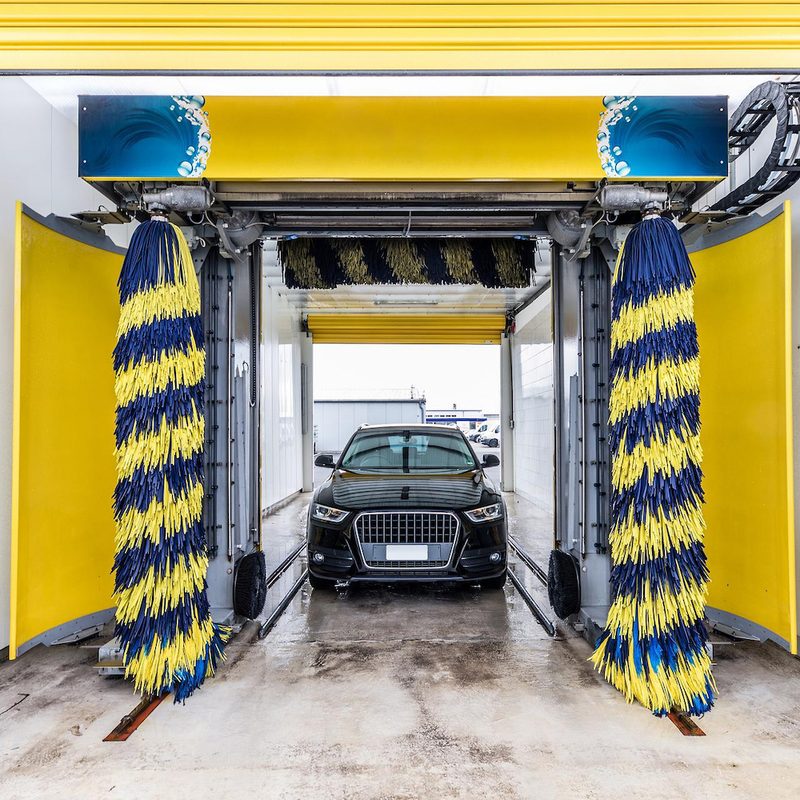 Small international car wash with blue and yellow brushes with an Audi waiting to be washed.