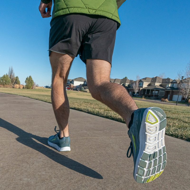 Man wearing Alta running shoes on condo complex walkway.