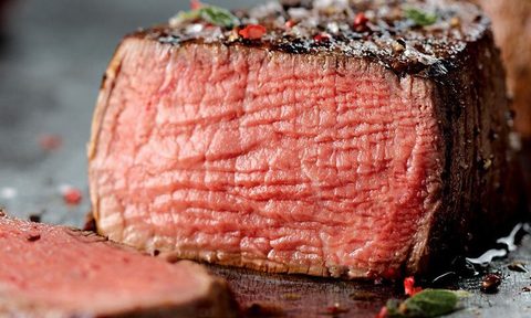 A sliced, cooked steak sits on a table.