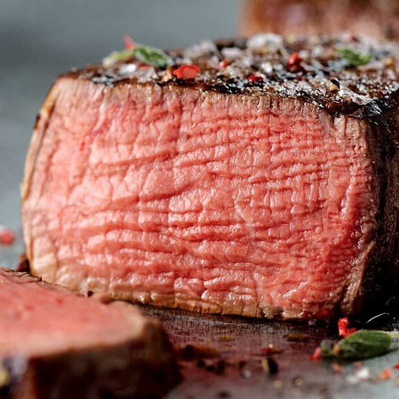A sliced, cooked steak sits on a table.