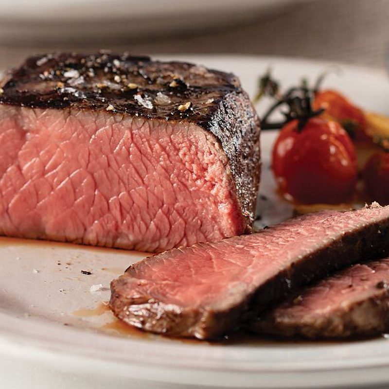A steak is cut into slices on a dinner plate.
