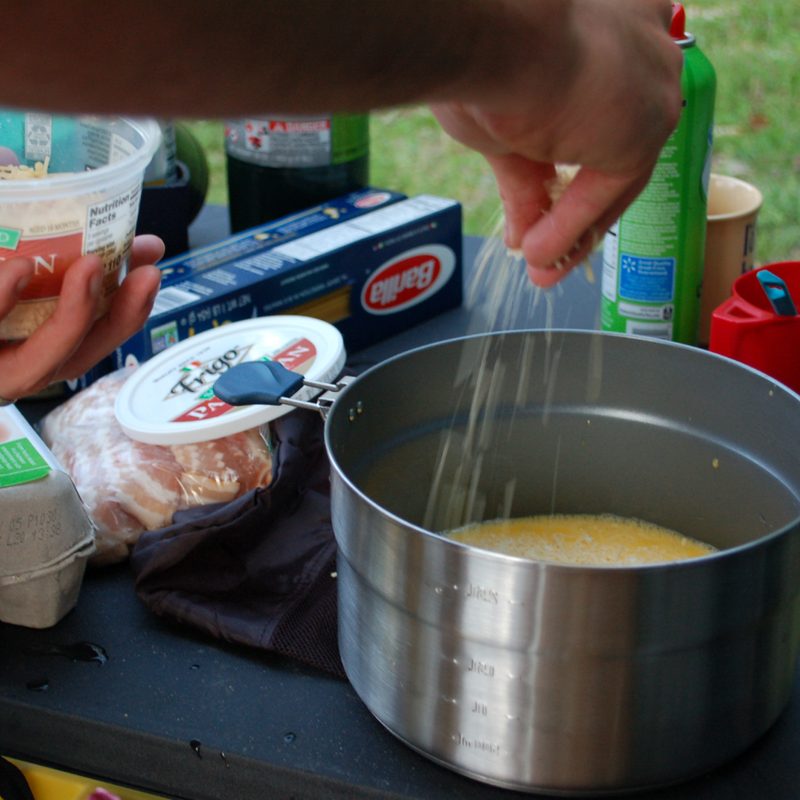 Adding cheese to eggs in a Quechua camp cook pot.