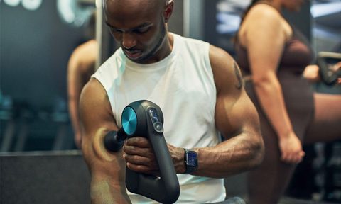 A man massages his arm with a Theragun Pro.