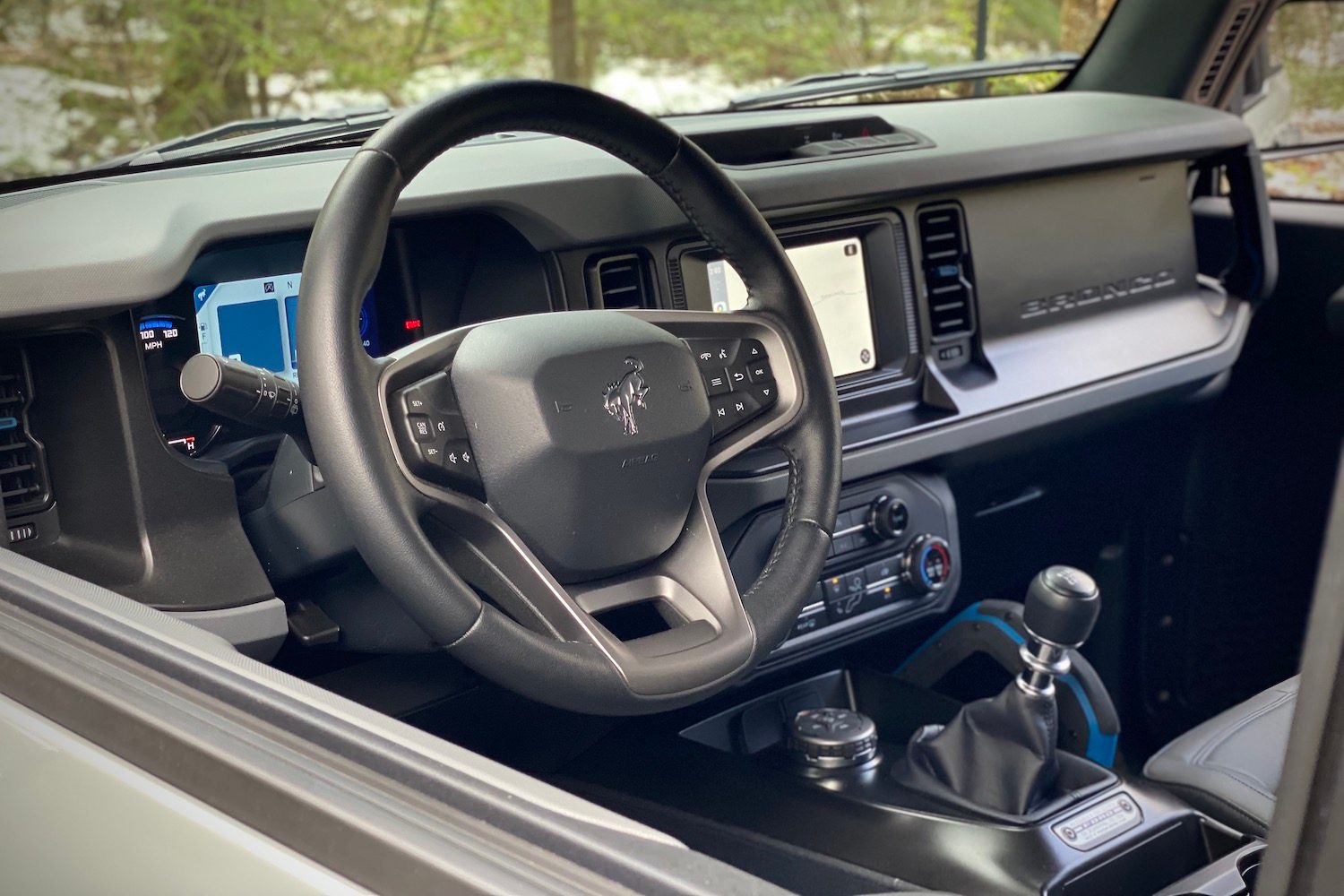 Close up of steering wheel in 2021 Ford Bronco with trees and snow in the back.