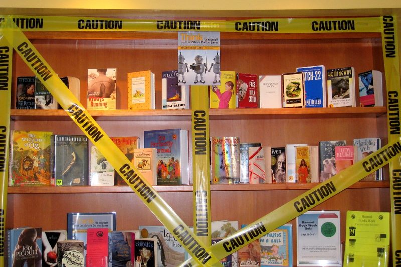 Caution tape atop library shelves containing banned books
