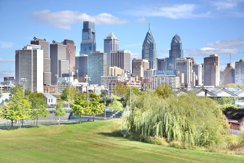Photo of the Philadelphia skyline taken from the South Street Bridge, showing Penn Park in the foreground.