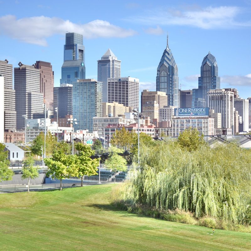 Photo of the Philadelphia skyline taken from the South Street Bridge, showing Penn Park in the foreground