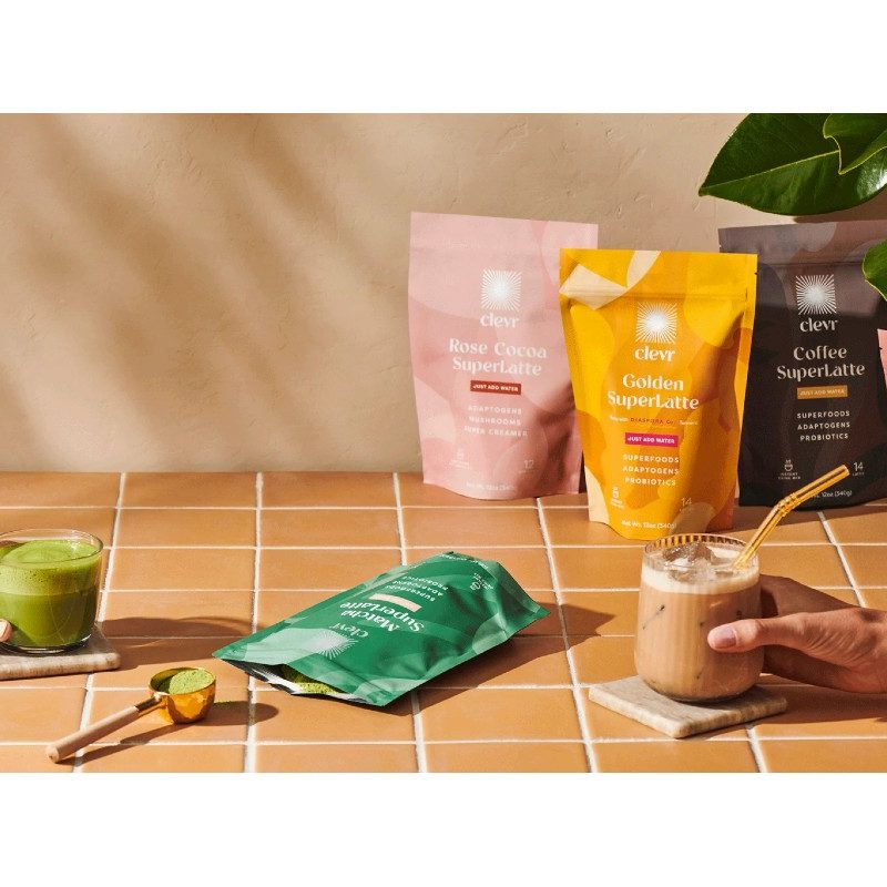 Various Clevr SuperLatte packages on a counterpoint and hands holding drinks