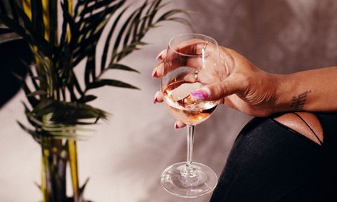 Holding a glass of white wine.