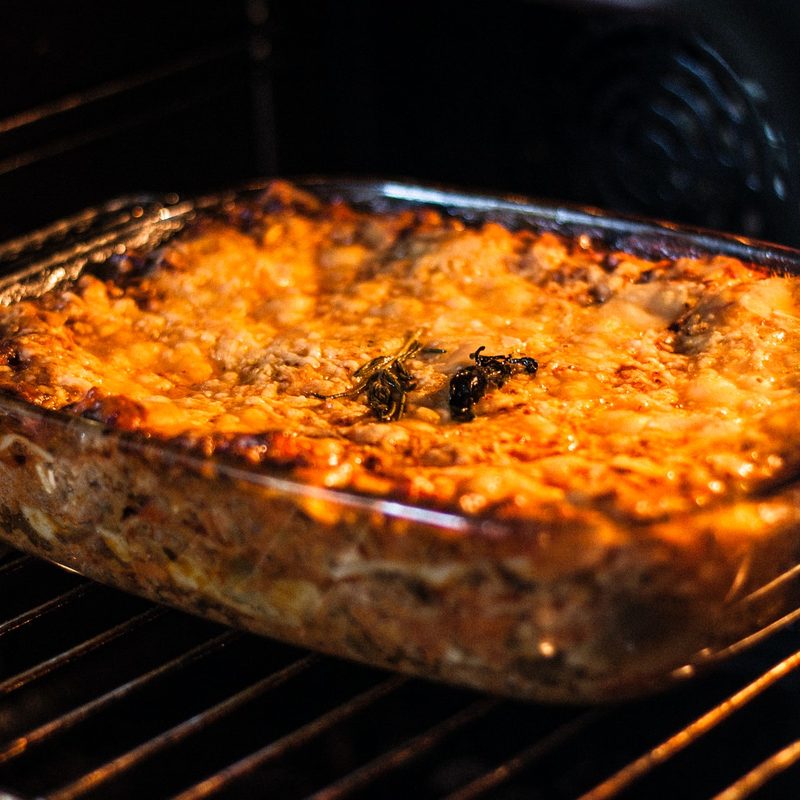 Cheesy lasagna in a glass baking dish in the oven