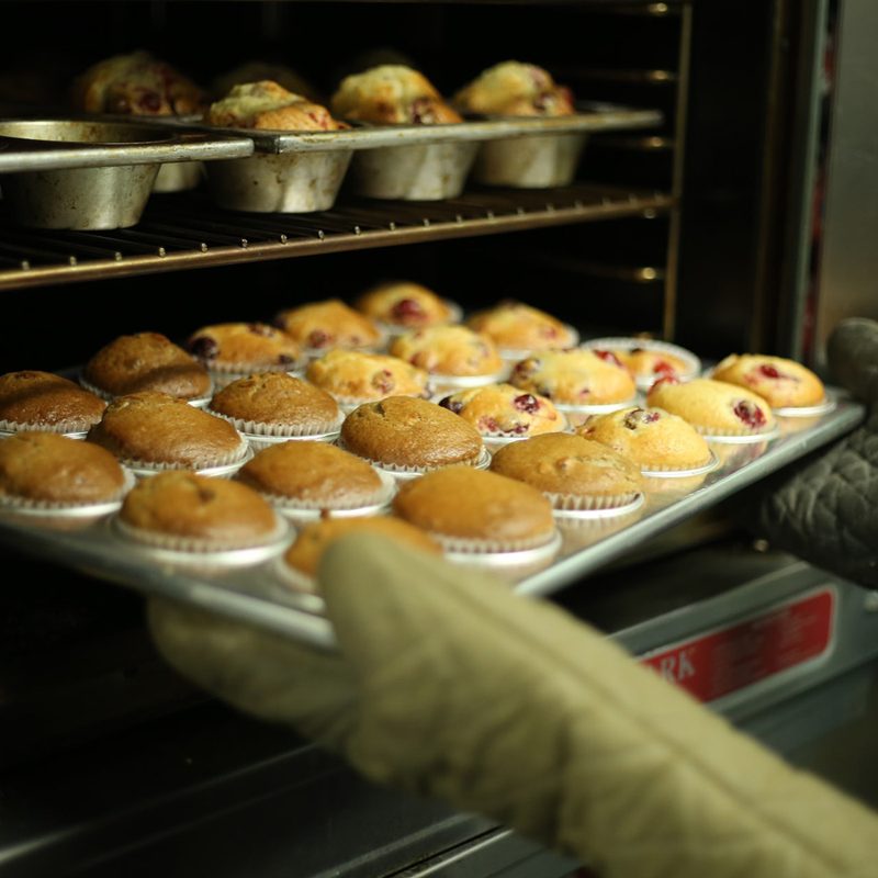 Removing muffins in a metal baking dish from the oven