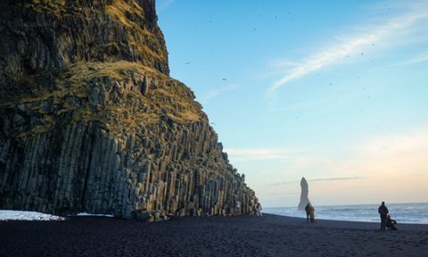 A few people enjoying the black sands of a beach near Vik, Iceland.