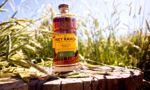 A bottle of Frey Ranch Rye Whiskey in front of some grains