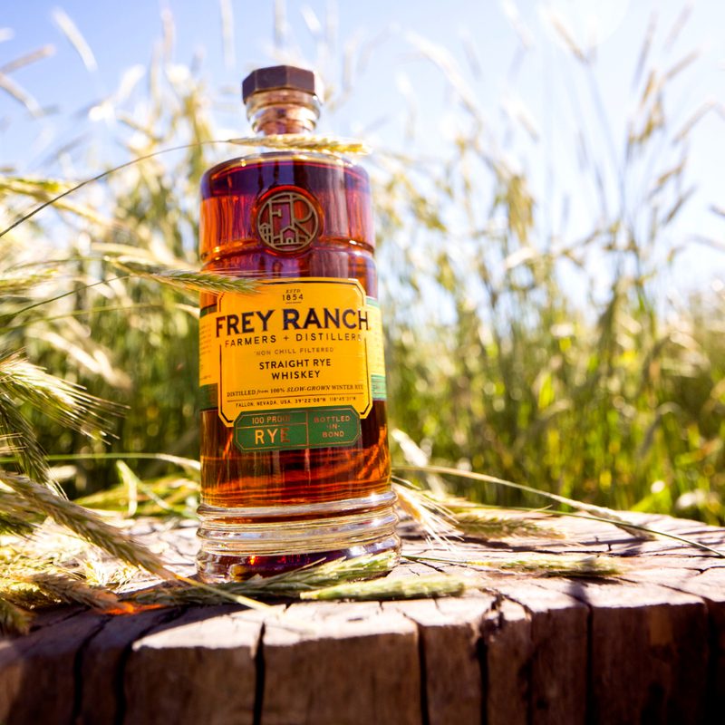 A bottle of Frey Ranch Rye Whiskey in front of some grains