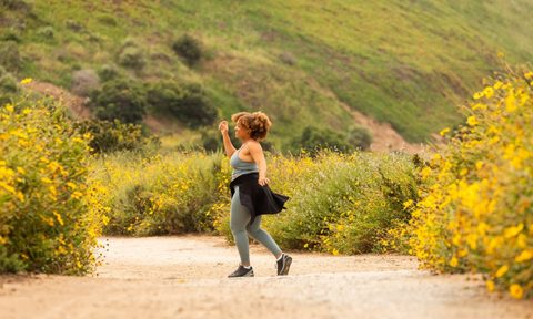 A woman strolls outdoors on a dirt road