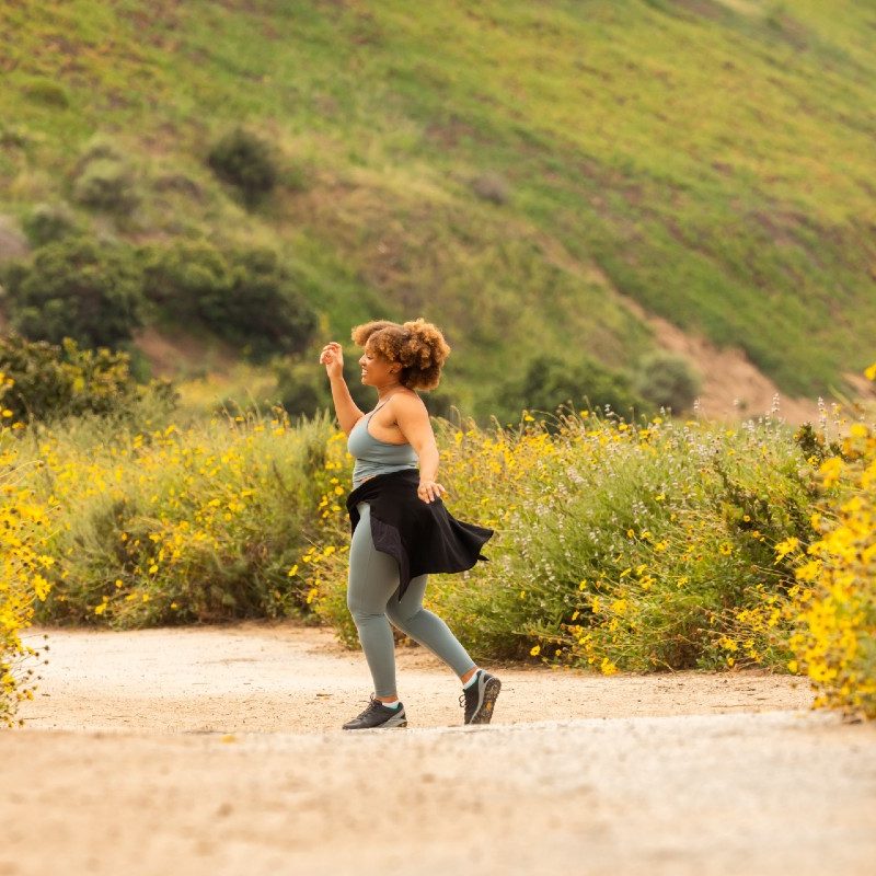 A woman strolls outdoors on a dirt road