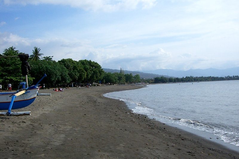 Boats and crowds of people gathered at Lovina Beach, a black sand beach in Indonesia.