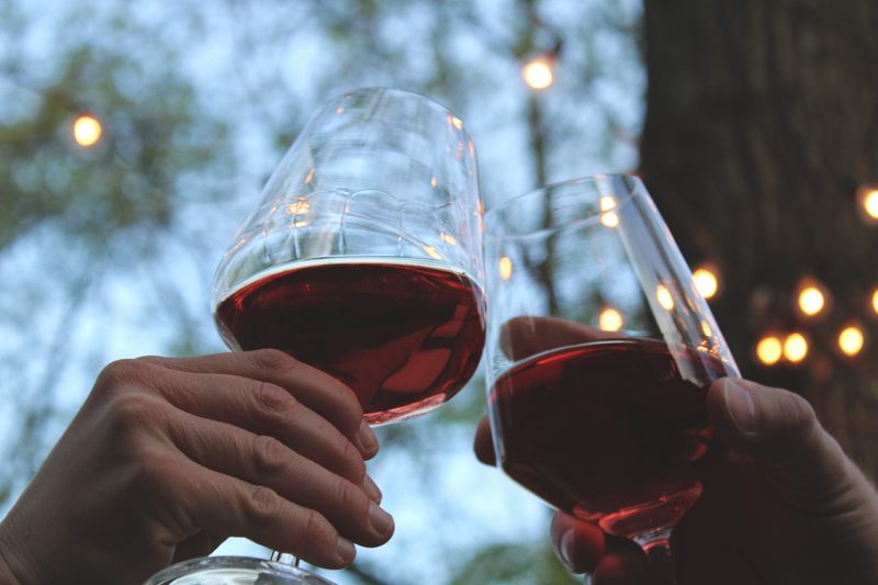 Clinking glasses of red wine.