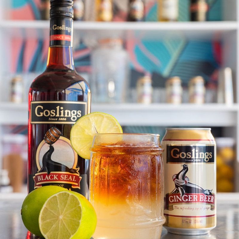 A Goslings Dark n' Stormy surrounded by lime, Black Rum, and Ginger Beer ingredients.