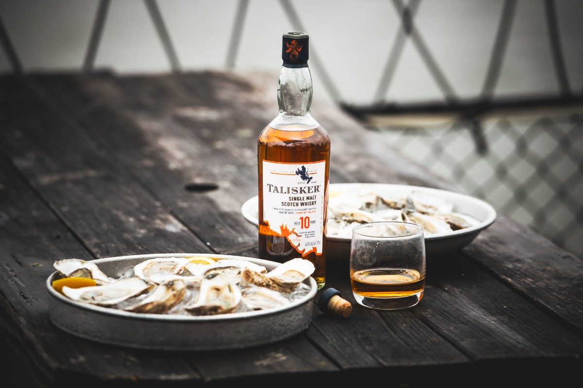 A bottle of Talisker Single Malt Scotch next to shucked oysters on ice aboard a fishing boat