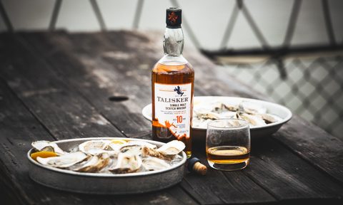 A bottle of Talisker Single Malt Scotch next to shucked oysters on ice aboard a fishing boat