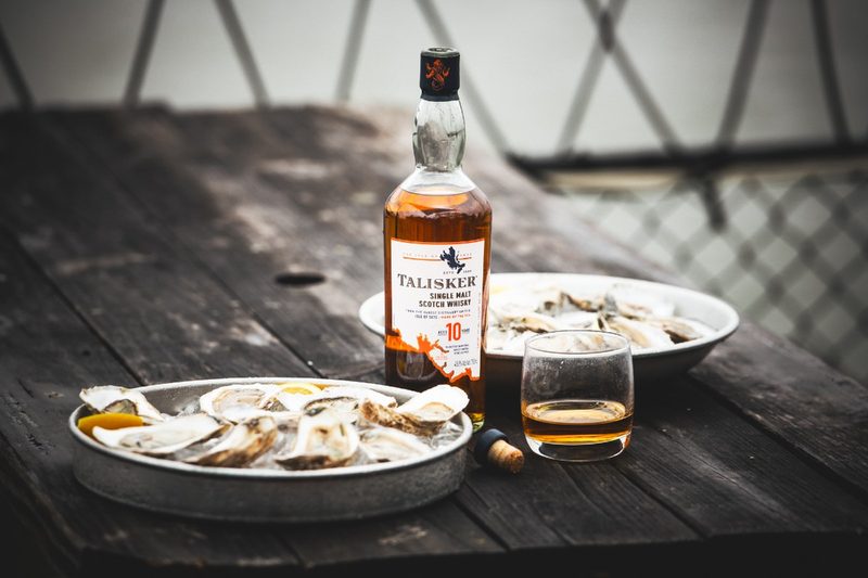 A bottle of Talisker Single Malt Scotch next to shucked oysters on ice aboard a fishing boat