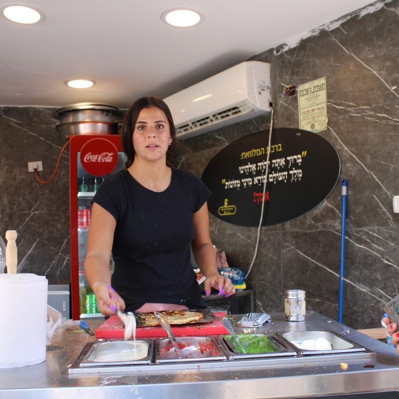 A woman makes malawah at her food stand at Carmel Market in Tel Aviv (Israel).