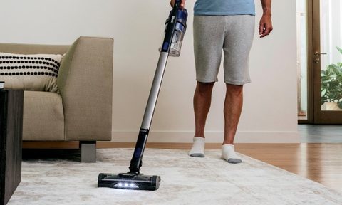 Woman using Shark Dyson cordless vacuum in kitchen