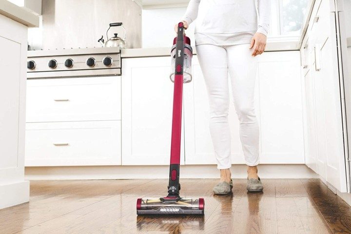 Woman using Shark Dyson cordless vacuum in kitchen