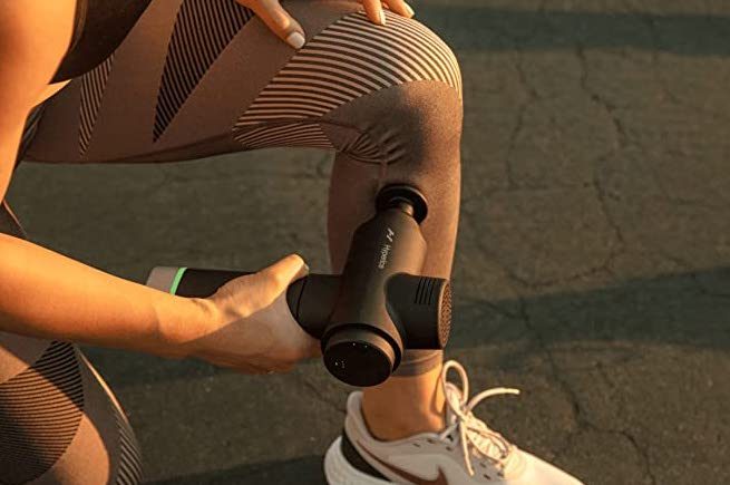 Woman using massage gun on her leg.