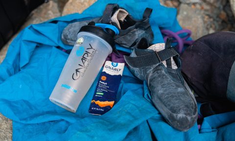 A climbing shoe next to an empty Gnarly water bottle and electrolyte bar.