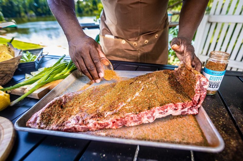 Chef Rodney Scott applying The Spice House's smoky barbecue hickory rub to ribs.
