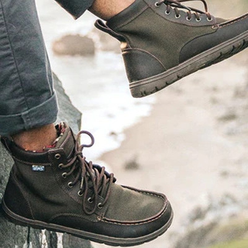 Lems Boulder Boots on a model, hanging from a cliff.