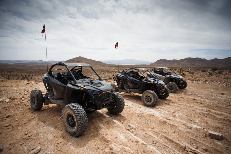 Polaris RZR Pro R and Turbo R from the front left side in the Mojave desert with mountains in the back on a dirt path.