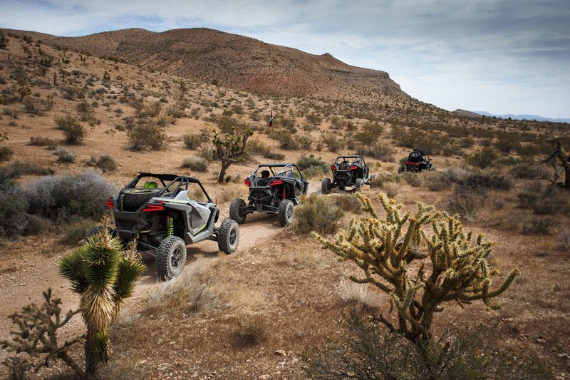Rear end of Polaris RZR Pro R and Turbo R in the Mojave desert with a mountain in the back on a dirt path.