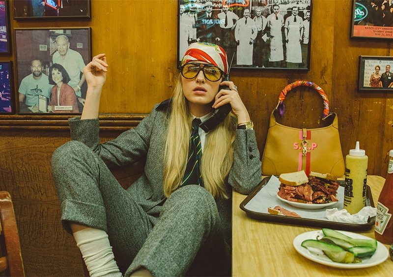 Woman in a suit sitting in a deli on the phone.