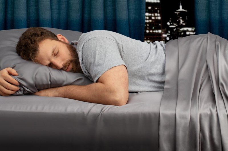 A man sleeps on a set of My Sheets Rock regulator bed sheets.