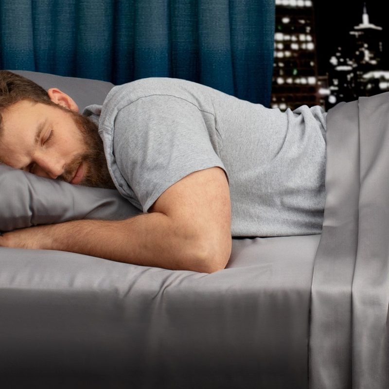 A man sleeps on a set of My Sheets Rock regulator bed sheets.