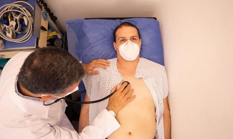 Doctor listening to man's heart.