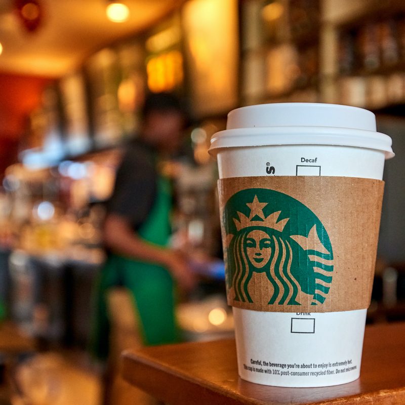 A Starbucks cup sitting on a counter inside of a store.